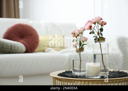 Candela bruciante e vasi con belle rose sul tavolo al coperto, spazio per il testo. Elementi interni Foto Stock