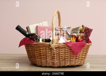 Cestino regalo in vimini con bottiglia di vino su tavolo in legno Foto Stock