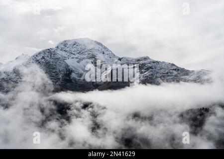 Una vista aerea dell'ipnotizzante montagna innevata coperta da soffici nuvole bianche Foto Stock