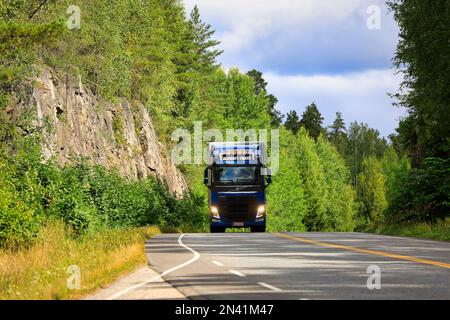 Blue Volvo FH elemento semirimorchio camion Trans Winsten Oy AB trasporta le merci lungo l'autostrada, abbaglianti ON brevemente. Salo, Finlandia. Luglio 23, 2021. Foto Stock