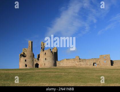 Castello di Dunstanburgh al sole d'inverno Foto Stock