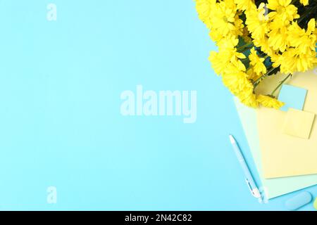 Cancelleria diversa scuola e bellissimi fiori gialli su sfondo azzurro, piatto con spazio per il testo. Buon giorno dell'insegnante Foto Stock