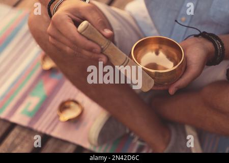 Uomo che usa la ciotola tibetana all'aperto, primo piano Foto Stock