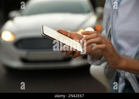 Donna che ordina un taxi con smartphone in città, closeup Foto Stock