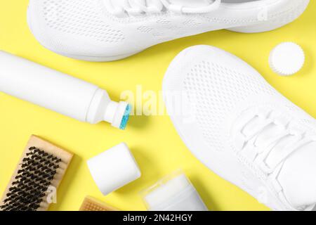 Composizione a posa piatta con calzature eleganti e accessori per la cura delle scarpe su sfondo giallo Foto Stock