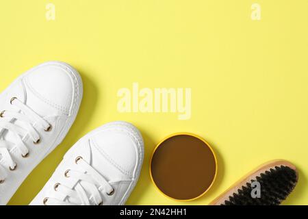 Composizione a posa piatta con scarpe eleganti e accessori per la cura delle scarpe su sfondo giallo, spazio per testo Foto Stock
