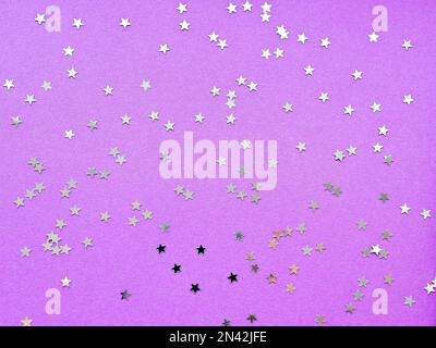 Sfondo delle vacanze con coriandoli in argento su sfondo viola. Piano di giacitura, vista dall'alto. Foto Stock