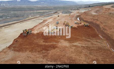 Escavatori in funzione. Caricamento di autocarri in un enorme sito minerario. Foto Stock