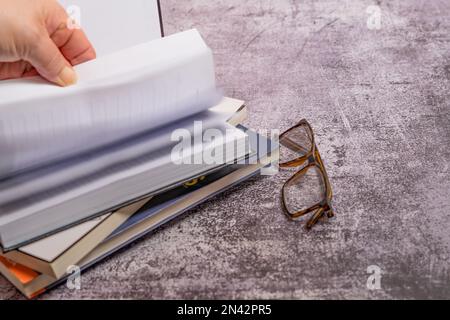 la mano della donna che gira le pagine di un libro con uno sfondo fuori-di-fuoco Foto Stock