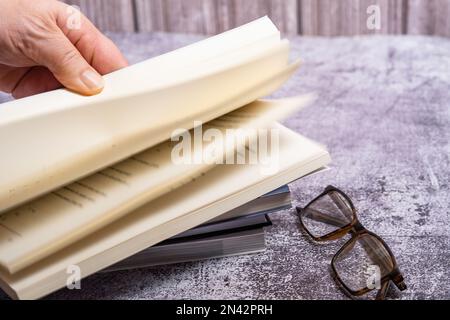 la mano della donna che gira le pagine di un libro con uno sfondo fuori-di-fuoco Foto Stock