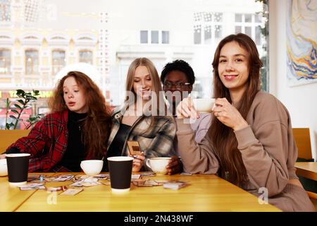 Amici multirazziali ragazze e ragazzi che si divertono a ridere bevendo tè al caffè in una caffetteria, giovani felici e diversi che parlano scherzando seduti insieme Foto Stock