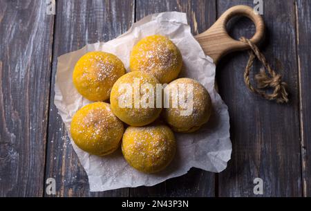 Panini di zucca freschi fatti in casa senza lievito con cardamomo cosparso di zucchero a velo su asse di legno, stile rustico, piatto Foto Stock