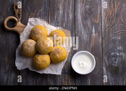 Panini di zucca freschi fatti in casa senza lievito con cardamomo cosparso di zucchero a velo su asse di legno, stile rustico, piatto, spazio Foto Stock