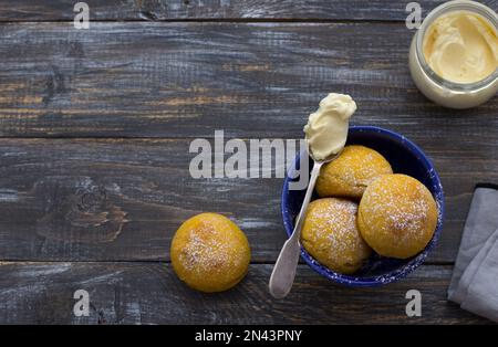 Panini di cardamomo di zucca freschi fatti in casa senza lievito con panna cosparsa di zucchero a velo su asse di legno, stile rustico, piatto, spazio Foto Stock