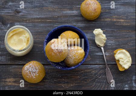 Panini di cardamomo di zucca freschi fatti in casa senza lievito con panna cosparsa di zucchero a velo su asse di legno, stile rustico, piatto Foto Stock