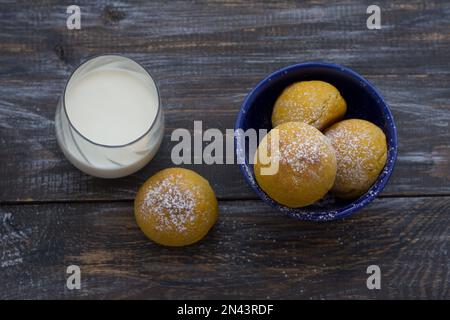 Panini di cardamomo di zucca freschi fatti in casa senza lievito con latte cosparso di zucchero a velo su asse di legno, stile rustico, piatto Foto Stock