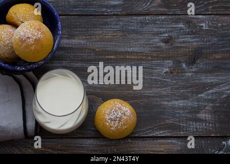 Panini di cardamomo di zucca freschi fatti in casa senza lievito con latte cosparso di zucchero a velo su asse di legno, stile rustico, piatto, spazio Foto Stock