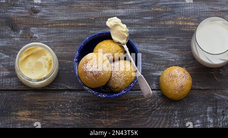 Panini di cardamomo di zucca freschi fatti in casa senza lievito con panna e latte cosparsi di zucchero a velo su asse di legno, stile rustico, piatto Foto Stock