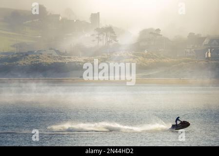 Dopo un'altra notte fredda nel Devon settentrionale, un moto d'acqua rompe la tranquillità di un fiume Torridge avvolto dalla nebbia mentre il sole inizia a bruciare la bassa nebbia marina sul villaggio costiero di Instow. Credit: Terry Mathews/Alamy Live News Foto Stock