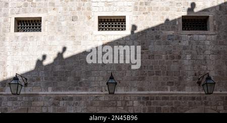 Il muro di pietra con piccole finestre e lampade. Monastero Domenicano a Dubrovnik, Croazia. Foto Stock