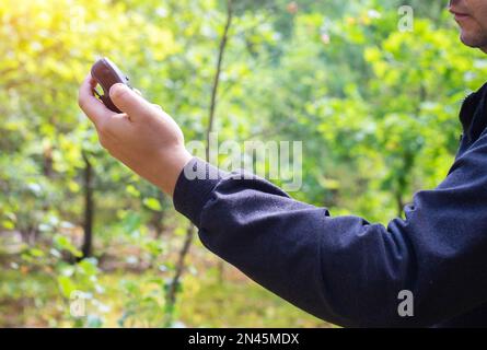 Forest Navigator nella foresta in mano di un uomo sullo sfondo di alberi verdi. Il concetto di orienteering per non perdersi in prima Foto Stock