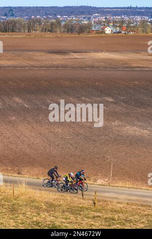 Ciclisti formazione su una strada in un paesaggio rurale Foto Stock