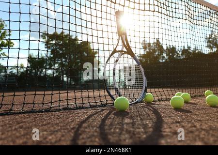 Palle da tennis e racchette vicino alla rete sul campo in argilla Foto Stock