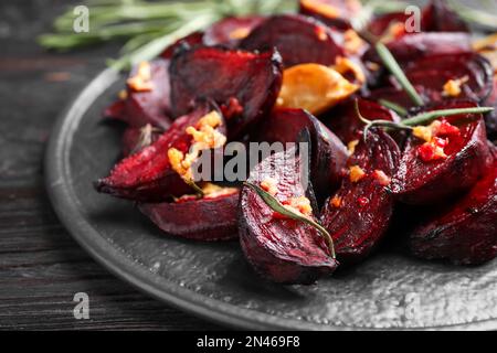 Fettine di barbabietola arrosto, aglio e rosmarino su tavola di legno nero, spicchio Foto Stock