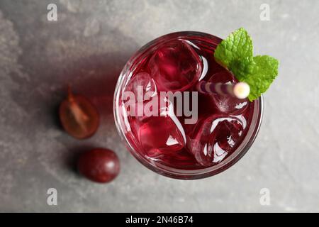 Deliziosa acqua di soda d'uva su tavolo grigio, piatto. Bevanda rinfrescante Foto Stock