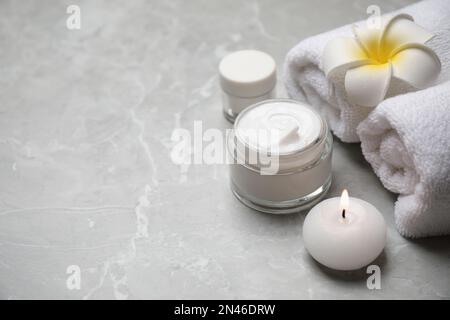 Composizione con asciugamani e prodotti per la cura della pelle su sfondo in marmo grigio chiaro, spazio per testo Foto Stock