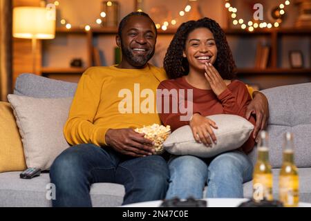 Coppia afro-americana gioiosa che guarda il film a casa Foto Stock