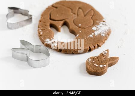 Pasta cruda di pan di zenzero pasquale con frese e farina. Preparazione di biscotti di Pasqua. Sfondo bianco. Vista ravvicinata Foto Stock