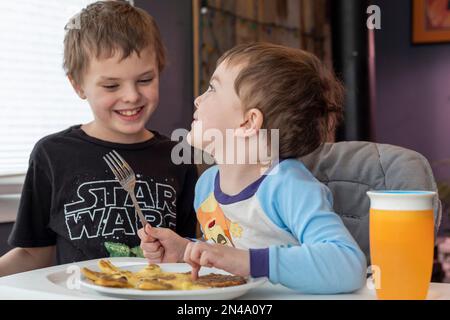 Denver, Colorado - Hendrix Hjermstad, 4 anni, si occupa della sua colazione mentre il suo fratello maggiore, Adam Hjermstad, Jr., 8 anni, guarda. Foto Stock