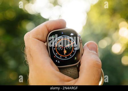 Londra, Regno Unito - 28 settembre 2022: Mano maschile che tiene in mano il nuovo Apple Watch Ultra Smartwatch contro lo sfondo bokeh sfocato con il quadrante di orologio Wayfinder Foto Stock