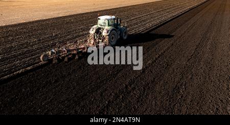 Una vista aerea di un trattore che arava un fertile campo agricolo con una ricca terra scura per colture e produzione alimentare con spazio di copia Foto Stock