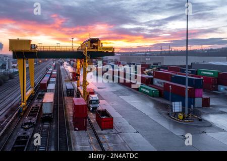 Vista aerea del terminale per container intermodale Freightliner di Leeds al tramonto con macchinari pesanti che caricano le scatole per container sul trasporto ferroviario Foto Stock