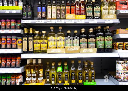 Fila di bottiglie di vetro di olio d'oliva italiano e greco su scaffali di negozi di alimentari del supermercato britannico scaffale in vendita in Gran Bretagna KATHY DEWITT Foto Stock