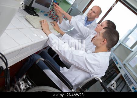 giovane studente in sedia a rotelle che si prepara per l'esame di chimica Foto Stock