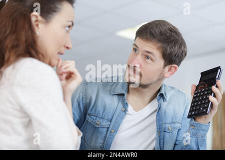 un uomo sconvolto che mostra una calcolatrice Foto Stock