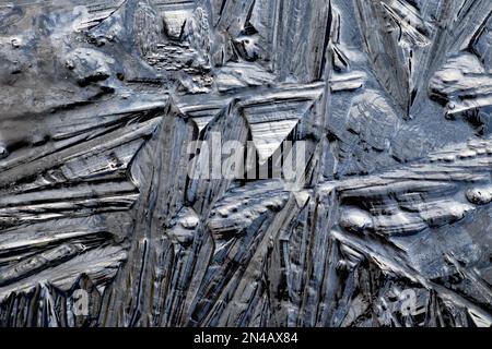 Schegge di ghiaccio d'acqua ghiacciata forma modelli guardando nero vista dall'alto fotografato in un contenitore scuro opaco il giorno freddo di congelamento UK KATHY DEWITT Foto Stock