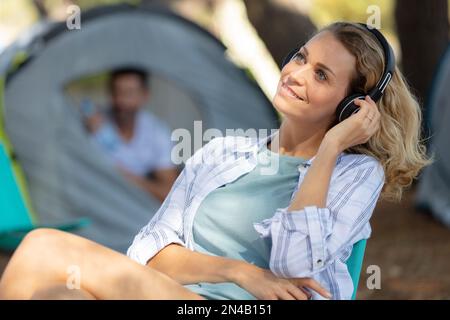 giovane donna che ascolta un giocatore di mp3 in un campeggio Foto Stock