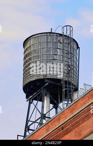 Grey Water Tower con scala sul Red Brick Building di NYC Foto Stock