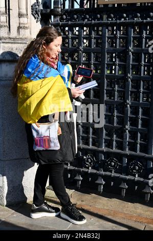 Londra, Regno Unito. Olha Plyushck, di Kyiv Ucraina, aspettò alla Carriage Gates, Houses of Parliament, per guardare l'indirizzo di Volodymyr Zelensky trasmesso dal vivo al Parlamento britannico sul suo cellulare. Foto Stock