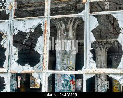 Il vetro vuoto nelle finestre si trova di fronte ad un impianto di maniacizzazione di automobili vuoto a Detroit, Michigan. Foto Stock