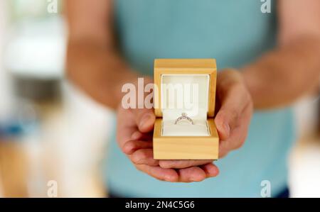 Uomo che tiene in mano e presenta un anello di aggancio scatolato aperto Foto Stock