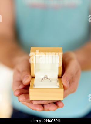 Uomo che tiene in mano e presenta un anello di aggancio scatolato aperto Foto Stock