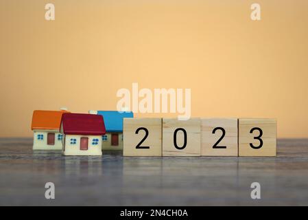 Blocchi di legno con il numero 2023 e casa. Previsione dei prezzi immobiliari, tendenze e cambiamenti, nuove sfide per l'economia e l'impatto sugli alloggi Foto Stock