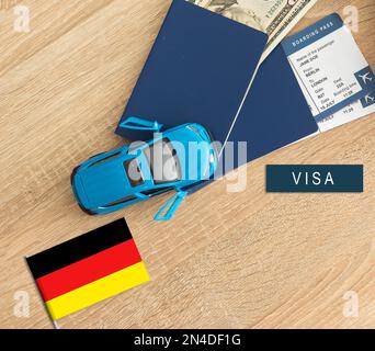 Bandiera della Germania con passaporto e aereo giocattolo su sfondo di legno. Concetto di viaggio in volo. Foto Stock