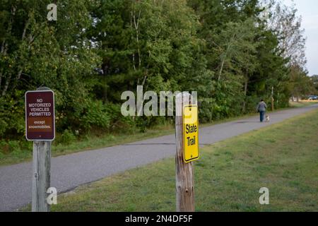 Cartelli su pali di legno lungo una pista pavimentata per biciclette, passeggiate e motoslitte nel Minnesota. Foto Stock