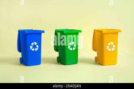 Serbatoio blu, giallo e verde per la raccolta differenziata dei rifiuti su sfondo giallo, riciclaggio dei rifiuti e conservazione dell'ambiente Foto Stock